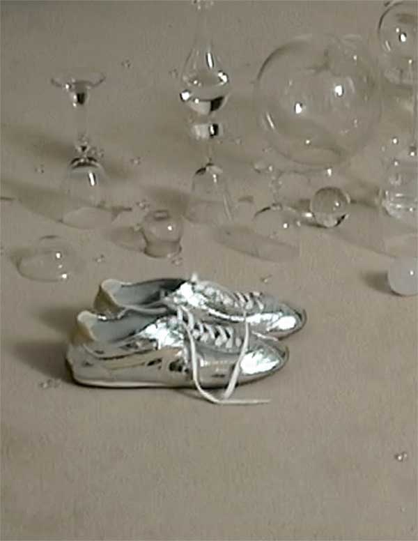 Close-up of Sandro silver Lightwave sneakers showcasing the reflective finish and sculpted sole, SS26 campaign.